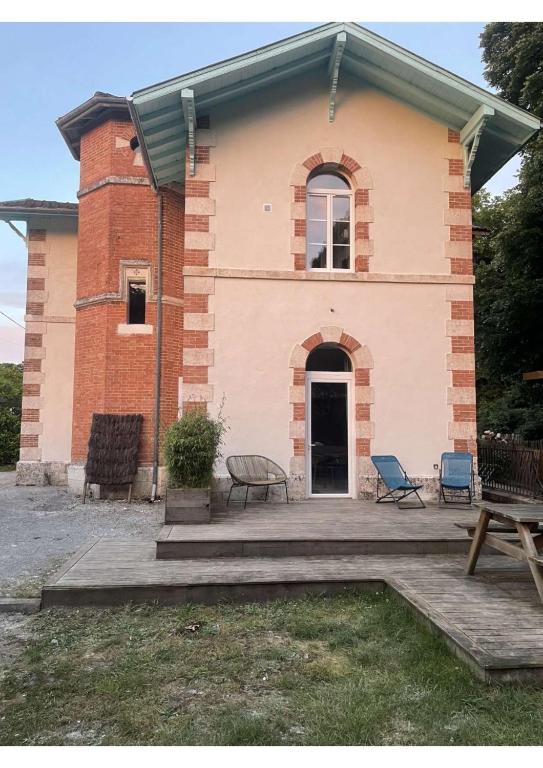 un bâtiment en briques avec des bancs devant lui dans l'établissement La demeure landaise, à Linxe