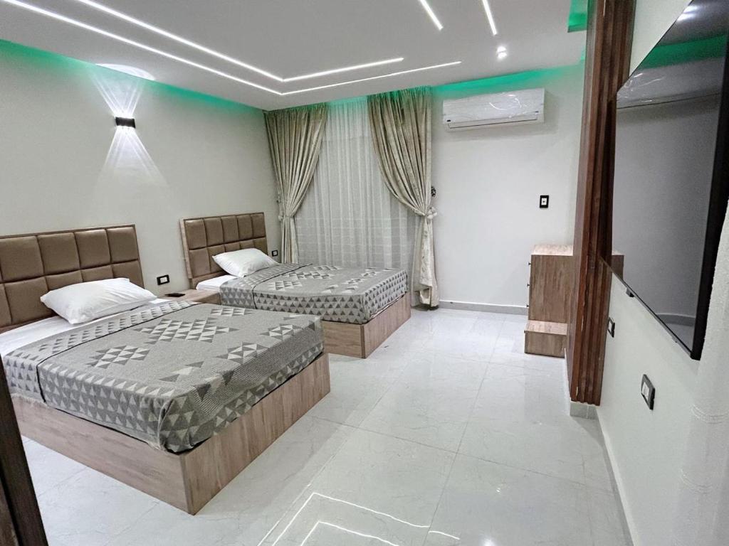 a bedroom with two beds and a flat screen tv at Comfy 2-Bedrooms Apartment in Cairo Sheraton airport in Cairo