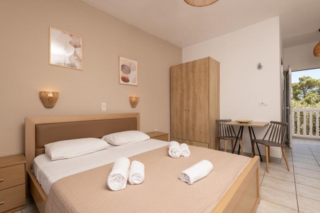 a bedroom with two beds and a table and a balcony at Akis Studios Alykes in Alykes