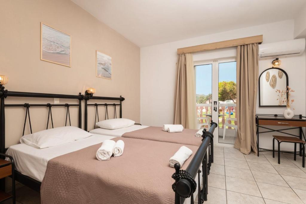 a bedroom with two beds and a desk and a window at Akis Studios Alykes in Alykes