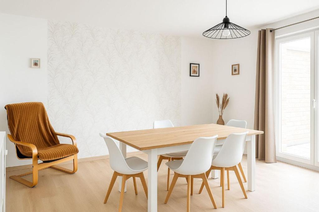 une salle à manger avec une table en bois et des chaises blanches dans l'établissement Appartement spacieux de 92m2, à Brest