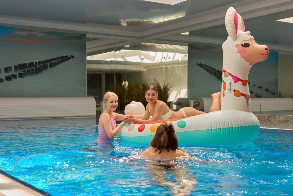 drei Frauen in einem Schwimmbad mit einem aufblasbaren Tier in der Unterkunft Waterlane Riverside - SPA, Pool, Gym &amp; Parking by Downtown Apartments in Danzig