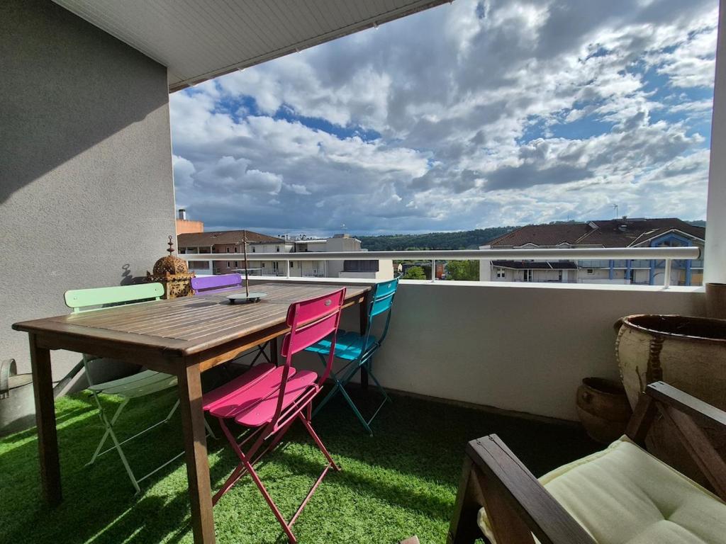 d'un balcon avec une table en bois et des chaises colorées. dans l'établissement Beau T3 lumineux avec terrasse et parking privé, à Billère