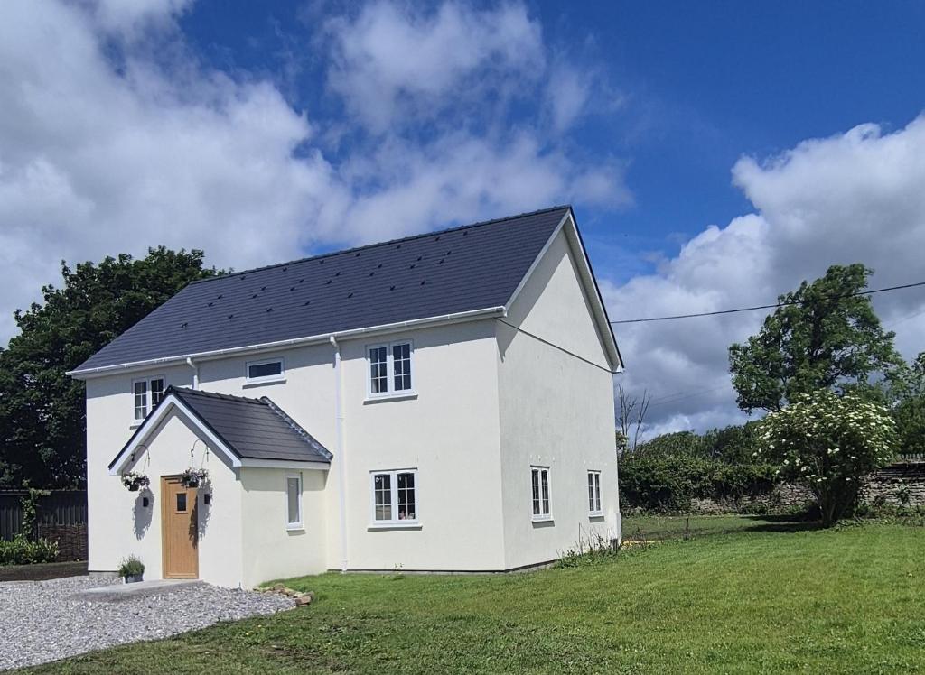 a white house with a black roof at Fig Tree Cottage in North Cornelly