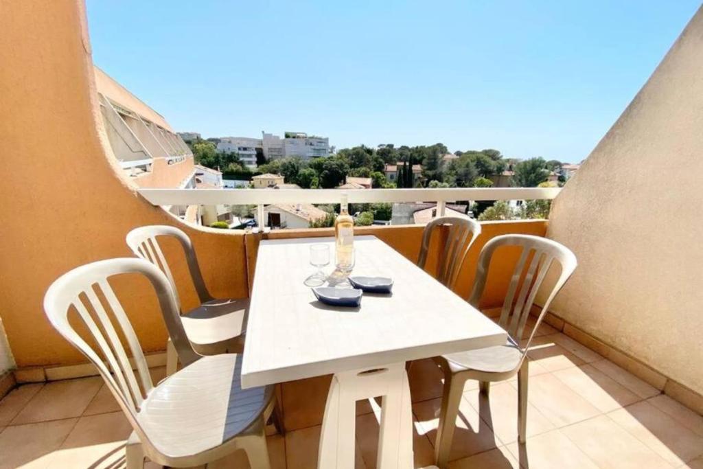 une table blanche et des chaises sur un balcon dans l'établissement Bright studio with balcony near the harbor, à Saint-Raphaël
