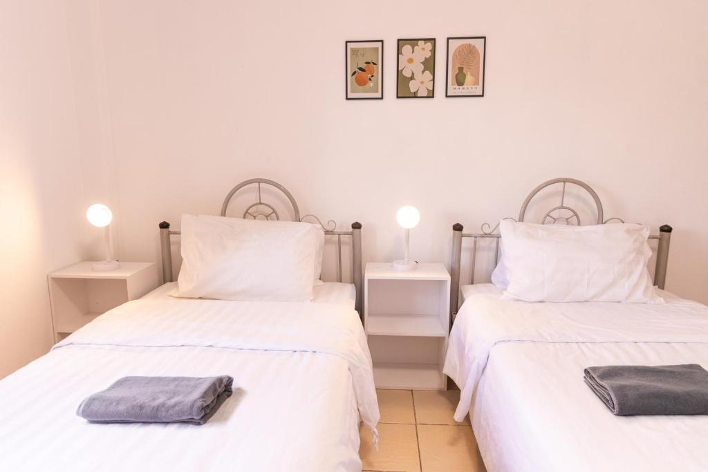 two twin beds in a room with white walls at Jida Place in Chiang Mai