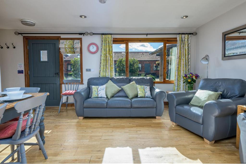 ein Wohnzimmer mit zwei blauen Sofas und einem Tisch in der Unterkunft Ash Cottage in Boston