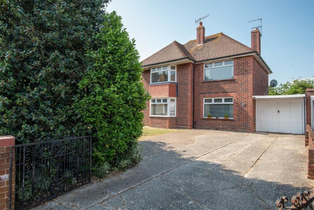 a brick house with a garage and a large tree at Westend House in Goring by Sea