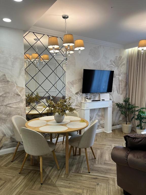 a dining room with a table and chairs and a tv at Family & Business Sauna Apartments Plac Wolności CENTRUM Downtow, - Piękny Apartament - 5 Bedroom with Private Sauna, Bath with Hydromassage, Parking, Catering Options in Kielce