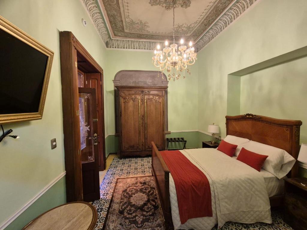 a bedroom with a bed and a chandelier at Hotel Boutique Del Buendia in San Luis Potosí