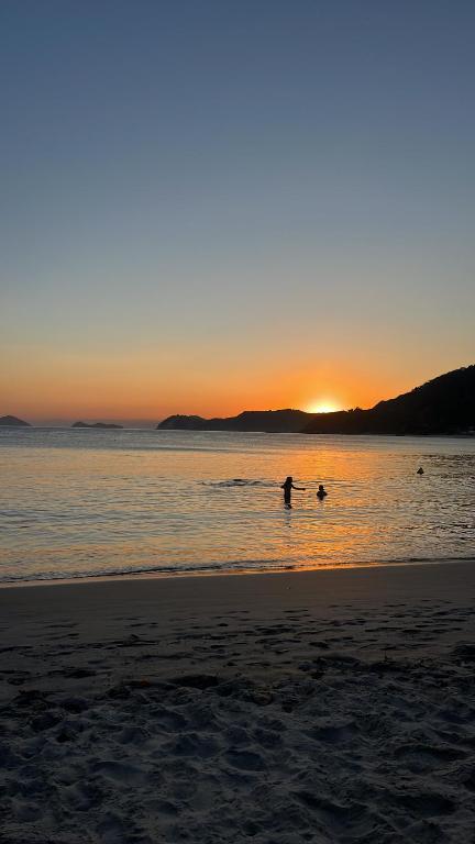 a person in the water at the beach at sunset at LINDO SOBRADO PERTINHO DA PRAIA - WiFi 600 MEGAS in Bertioga