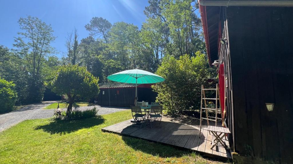 une table et des chaises sous un parasol sur une terrasse dans l'établissement La Grange au beau milieu des Pins, à Lacanau