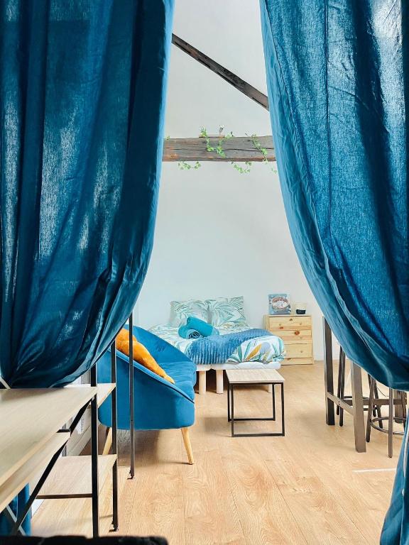 Cette chambre comprend 2 lits et des rideaux bleus. dans l'établissement Le Nid Suspendu, à Orléans