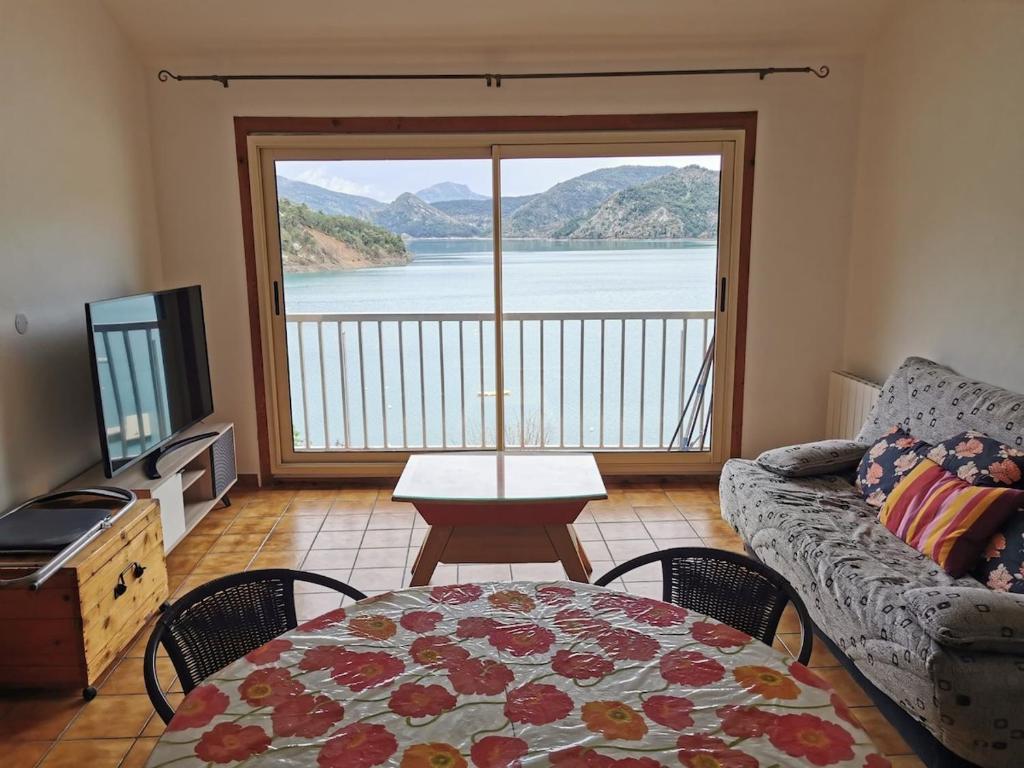 a living room with a couch and a table and a large window at Bord de Lac in Saint-Julien-du-Verdon