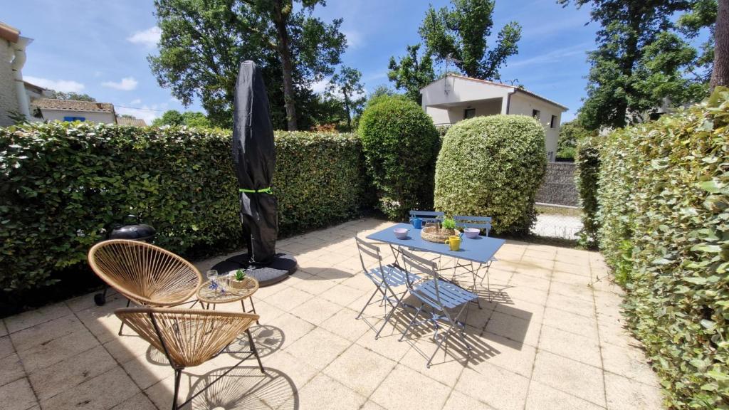 un patio avec une table, un parasol et des chaises dans l'établissement Meschers sur Gironde - MAISONNETTE de VACANCES - terrasse - proche PLAGE, à Meschers-sur-Gironde