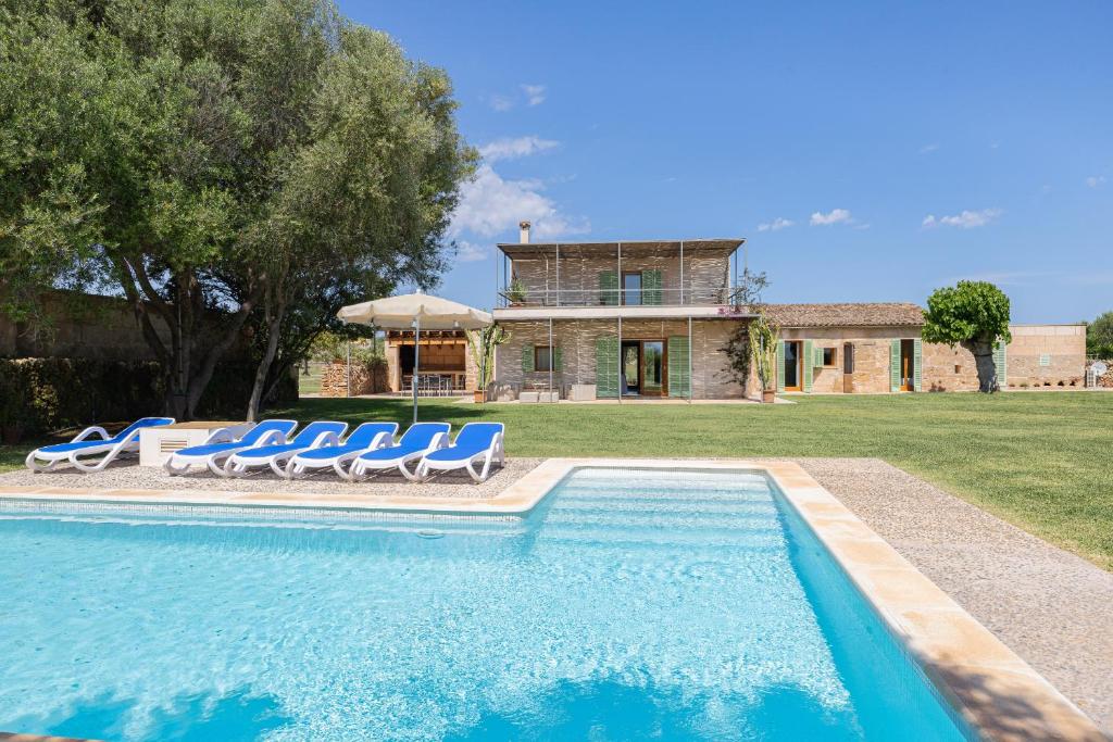 a swimming pool with chairs and a house at Can Cadernera by Rentallorca in Can Picafort