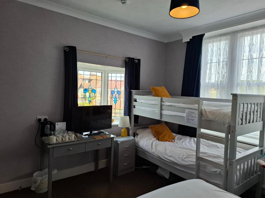 a bedroom with two bunk beds and a desk with a computer at Westbrook Lodge Guest House in Margate