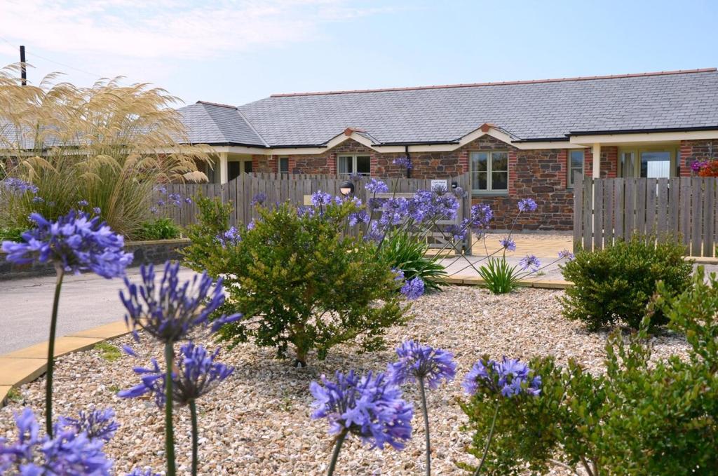 a garden with purple flowers in front of a house at Hazel - 3 Bed accessible holiday cottages in Tregoney