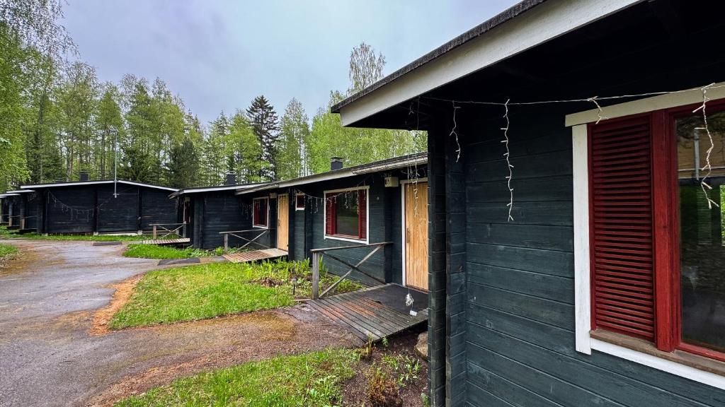 Un grupo de edificios negros con árboles al fondo. en Kyyronkaita, en Mikkeli