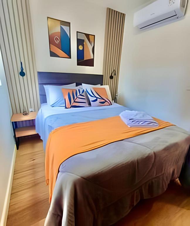 a bedroom with a bed with an orange blanket at Novinho, Lindo e Moderno C/ Ar Cond. in Curitiba
