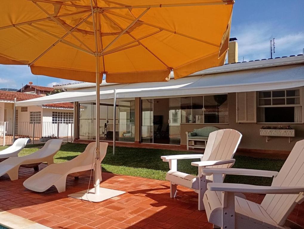 patio con sedie e ombrellone di Casa Região Privilegiada próx. ao Centro e Clube Campo. a Joanópolis