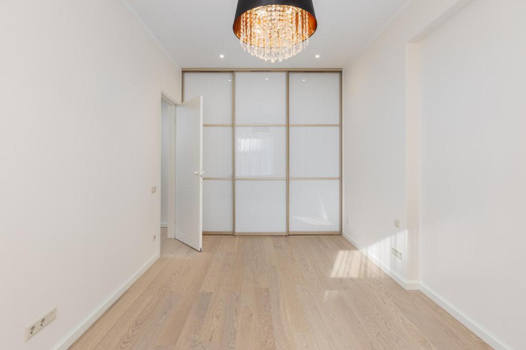 an empty hallway with a chandelier and white walls at Gatve apartment in Rīga