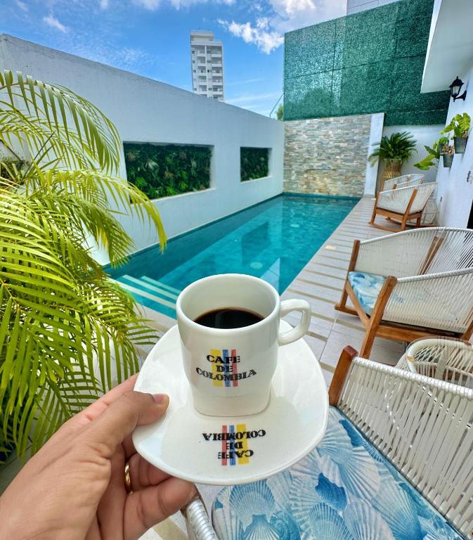 a person holding a cup of coffee on a patio at Le MARIE B&B in Cartagena de Indias