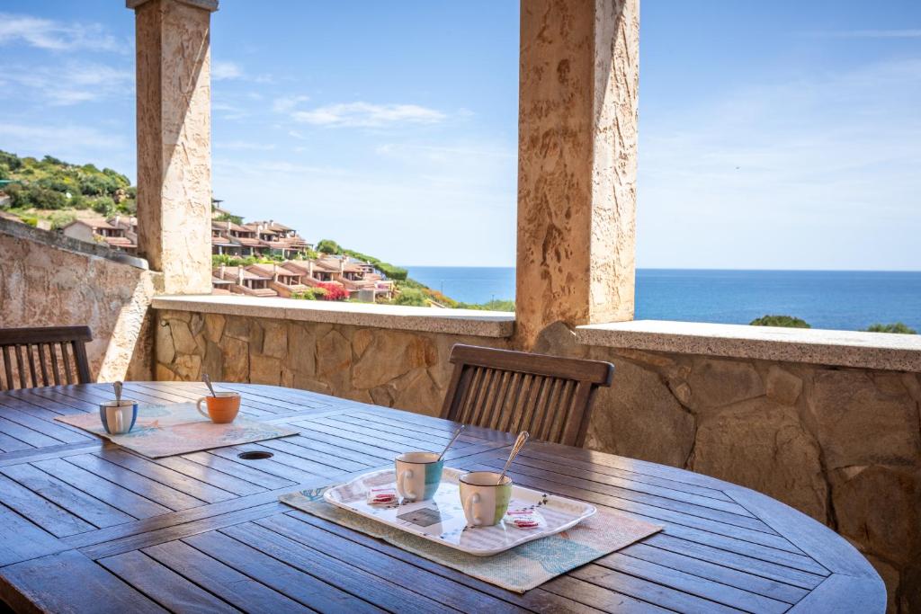 a wooden table on a balcony with a view of the ocean at GuestHost - Bedà House in Porto Carollo