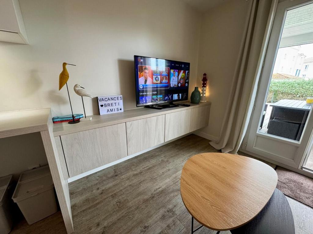 a living room with a tv and a wooden table at Entre mer & piscine Maison familiale pour 6 in Brétignolles-sur-Mer