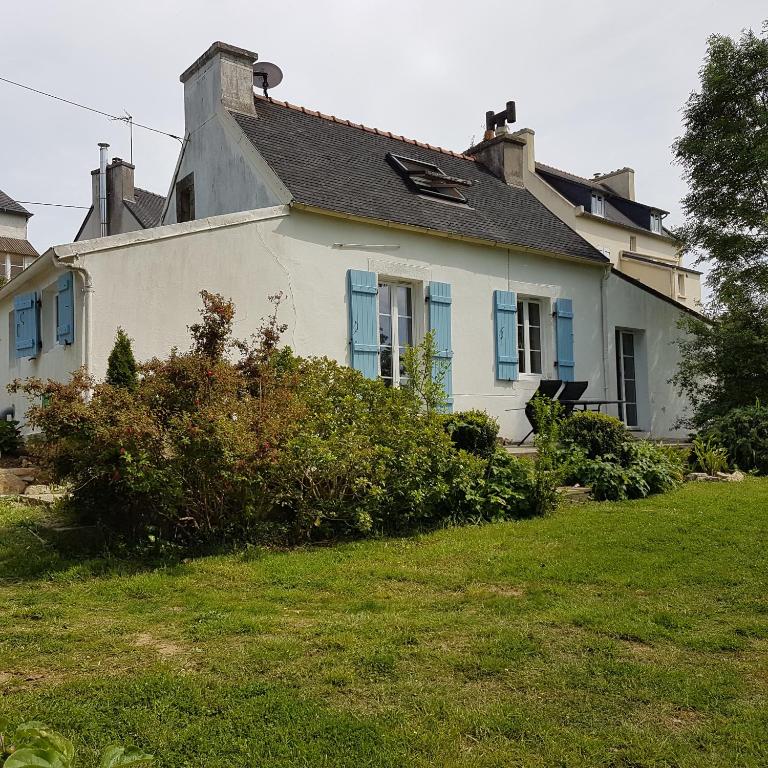 une maison blanche avec des fenêtres bleues et une cour dans l'établissement Camaret maison grand jardin, à Camaret-sur-Mer