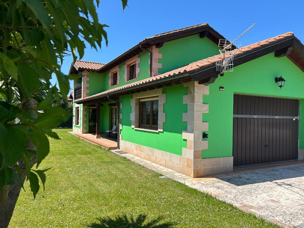 a green house with a garage at Refugio privado en plena naturaleza cántabra in Ibio