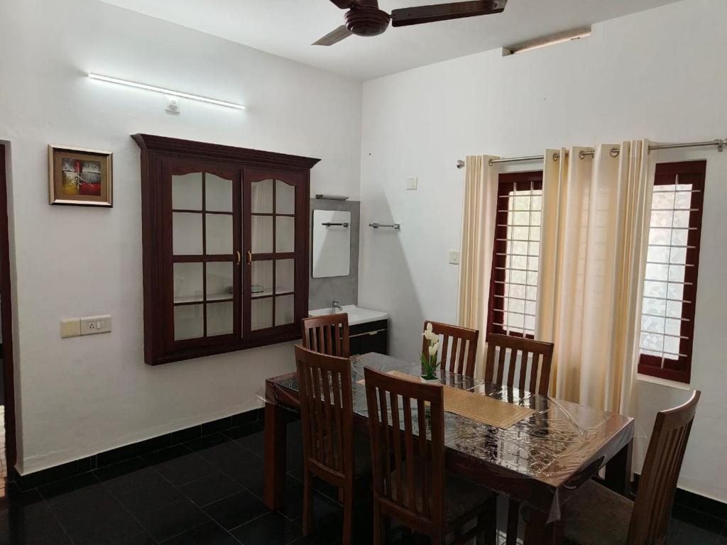 a dining room with a wooden table and chairs at Palm Villa in Trichūr