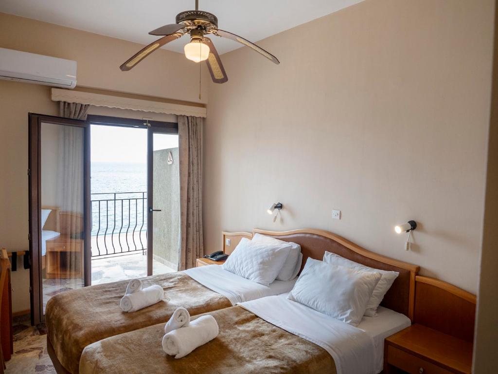 a hotel room with two beds and a balcony at Sappho Hotel in Skala Eresou