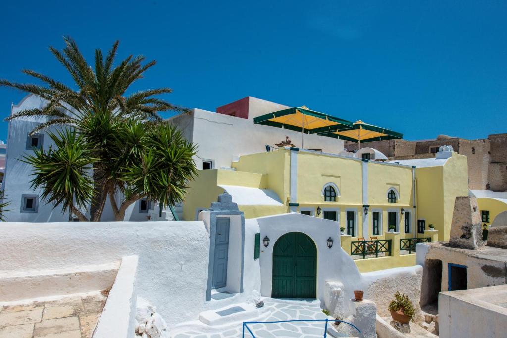 una casa con una puerta verde y palmeras en Christos Apartments Oia, en Oia