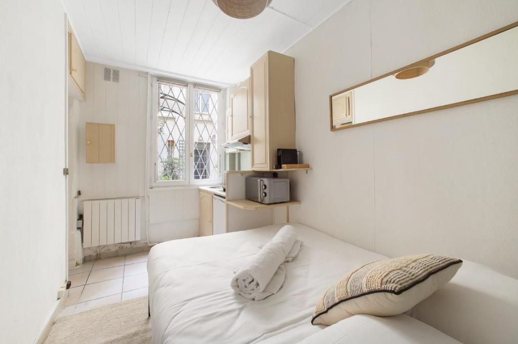 une chambre blanche avec un lit et une fenêtre dans l'établissement Paris Marais Ste Catherine, à Paris