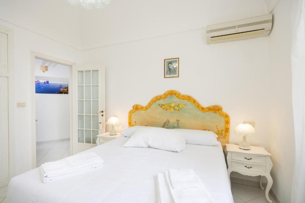 Un dormitorio blanco con una cama blanca y dos lámparas. en CapriGetaway - La Rosa Bianca, en Capri