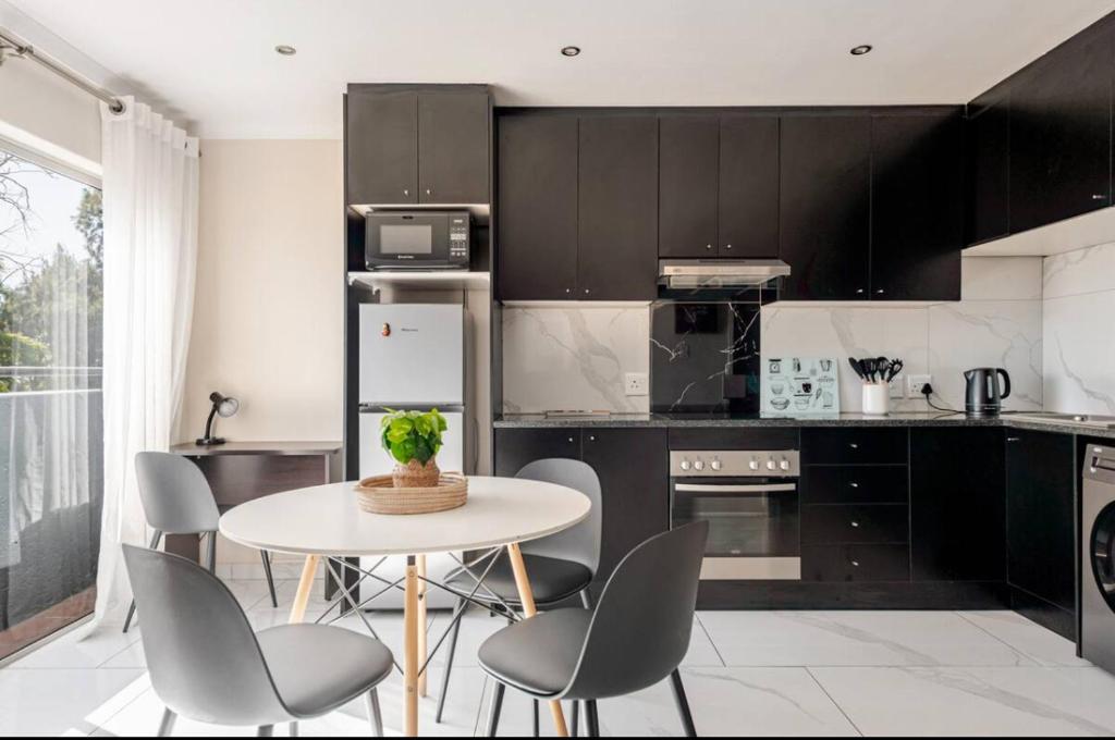 a kitchen with a table and chairs in a room at Cozy loft with swimming pool in Johannesburg