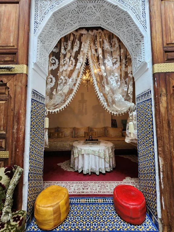 a room with a table and two ottomans at Riad Bennouna in Fez
