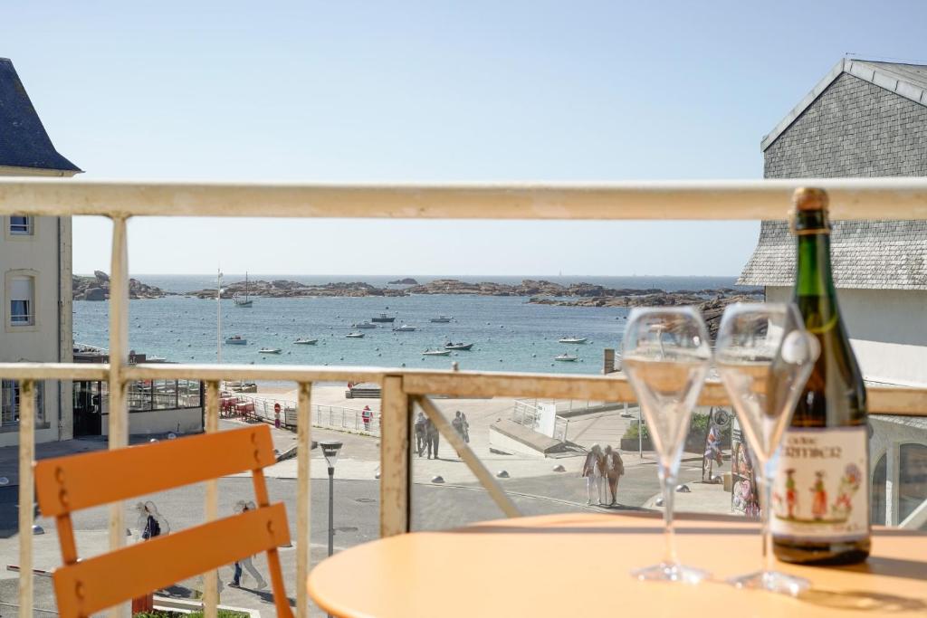 een tafel met twee wijnglazen en uitzicht op de oceaan bij Le 123 Armoric - Balcon vue mer - 50m de la plage - Confort et moderne - 70m2 in Trégastel