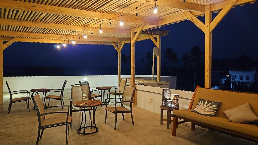 a patio with tables and chairs and a couch at Zanzicrown in Nungwi
