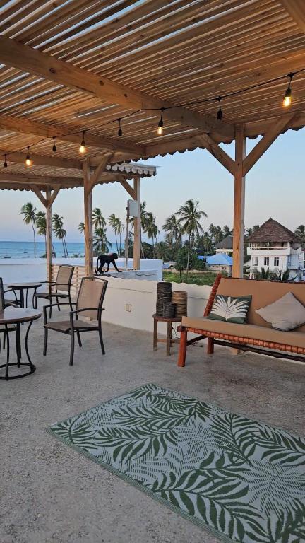 a patio with a couch and tables and chairs at Zanzicrown in Nungwi