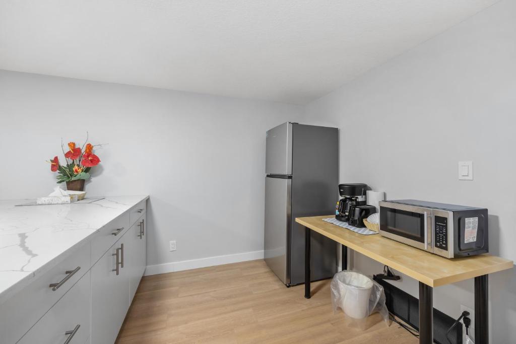 a kitchen with a table with a microwave and a refrigerator at Flora's House in Calgary