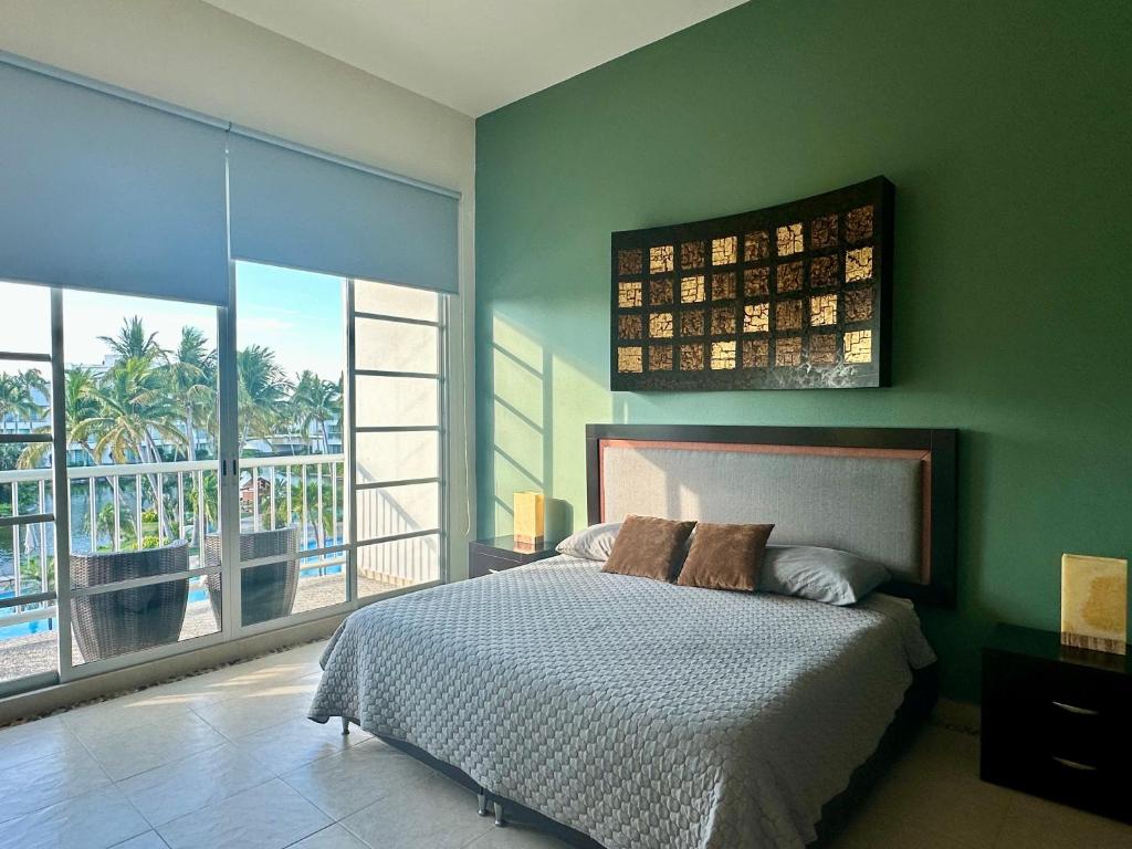 a bedroom with green walls and a bed with a balcony at Casa del Sol Lujoso Departamento en Acapulco in Acapulco