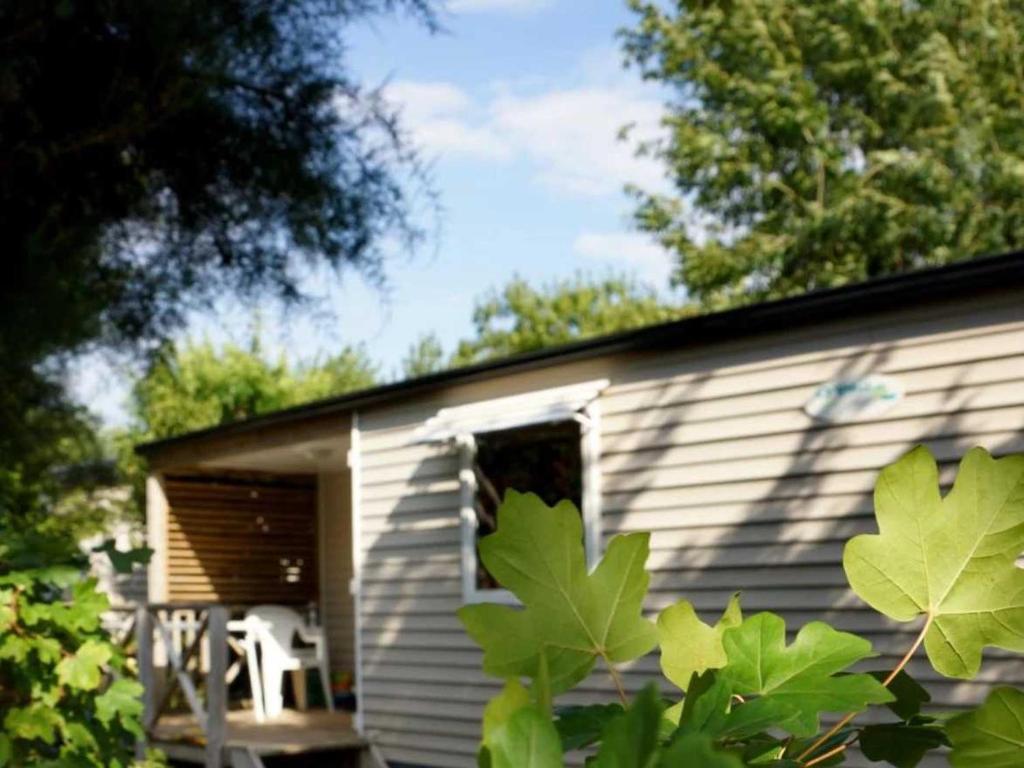 a cabin with a window and a white chair in it at Camping 4 étoiles - Piscine - cbgcaig in Notre-Dame-de-Monts