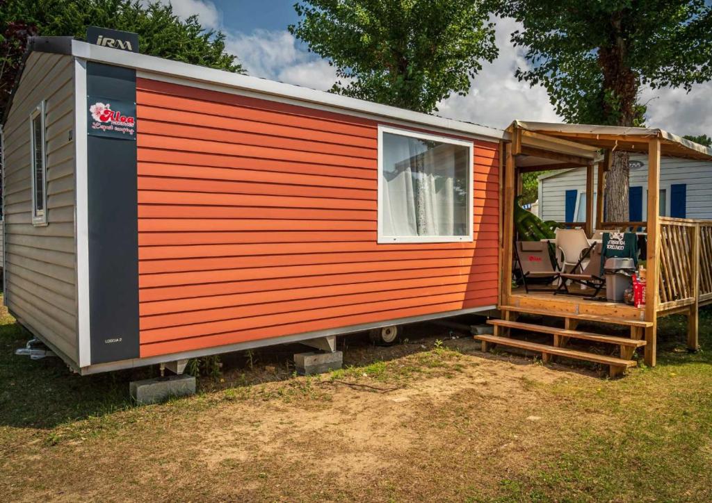 ein rotes und orangefarbenes winziges Haus mit einer Veranda in der Unterkunft Camping 4 étoiles - Parc aquatique - ccadfdf in Saint-Jean-de-Monts