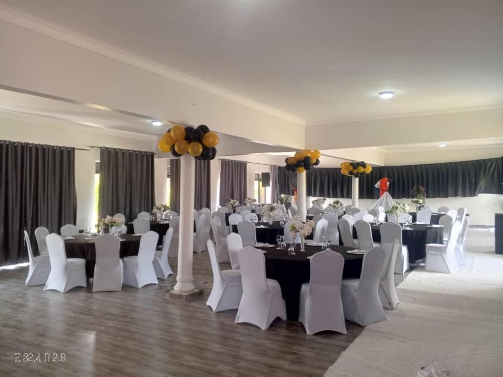 a banquet hall with white tables and white chairs at Kacoke Madit Hotel and Cultural Centre, Gulu in Gulu