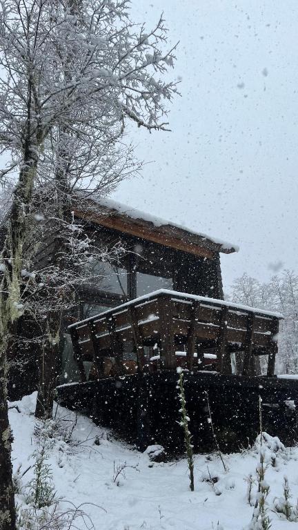 a snow covered bench in front of a cabin at Refugio Vista Sierra Nevada in Malalcahuello