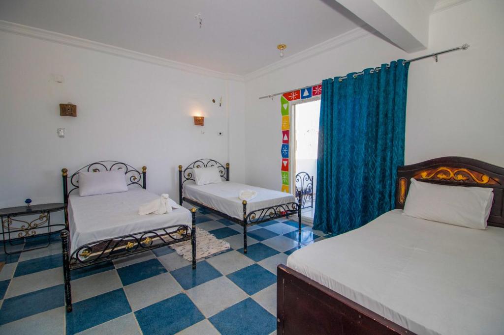 Un dormitorio con dos camas y suelo de cuadros. en Kulaih nubian guest house, en Asuán