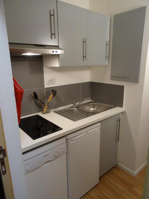 une petite cuisine avec des armoires blanches et un évier dans l'établissement Joli studio rénové 5p avec parking à La Mongie Tourmalet, à Bagnères-de-Bigorre