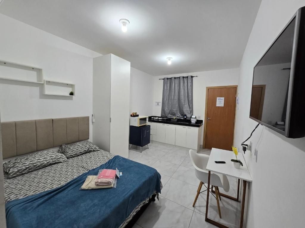a bedroom with a bed and a desk and a television at Flat completo a 5 minutos apé de mercado, farmácia in Aparecida de Goiania